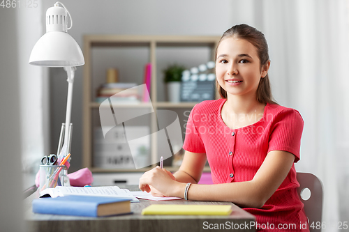 Image of smiling teenage student girl with books at home