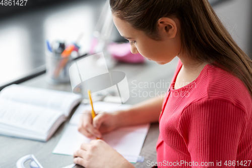 Image of student girl with ruler drawing line in notebook