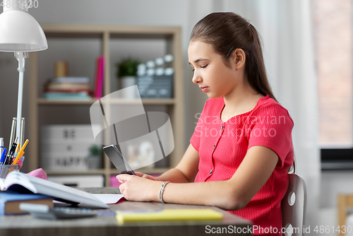 Image of girl with smartphone distracting from homework