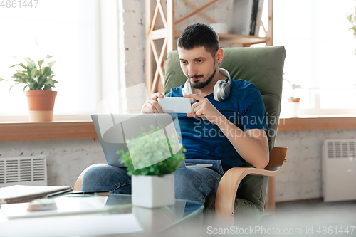 Image of Young focused man studying at home during online courses or free information by hisself