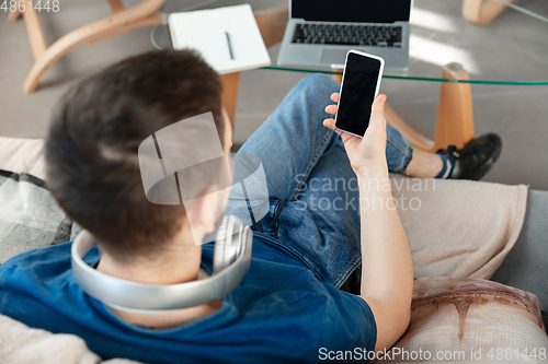 Image of Young focused man studying at home during online courses or free information by hisself