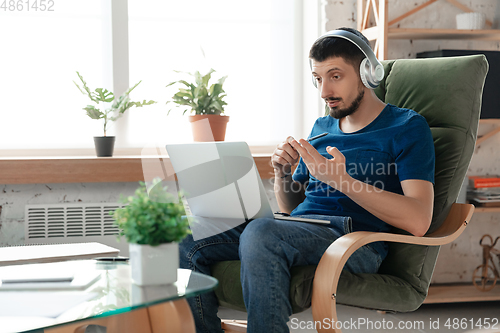 Image of Young focused man studying at home during online courses or free information by hisself