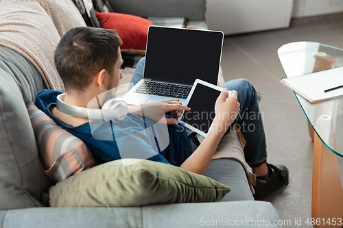 Image of Young focused man studying at home during online courses or free information by hisself