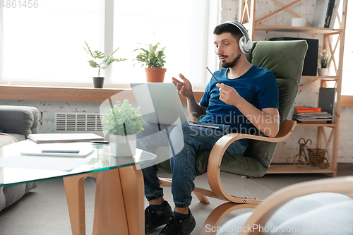 Image of Young focused man studying at home during online courses or free information by hisself