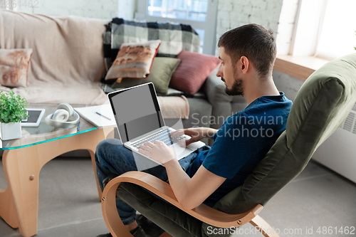 Image of Young focused man studying at home during online courses or free information by hisself