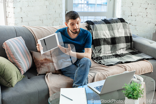 Image of Young focused man studying at home during online courses or free information by hisself