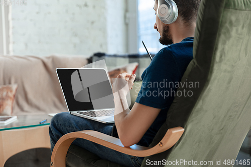 Image of Young focused man studying at home during online courses or free information by hisself