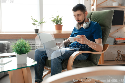 Image of Young focused man studying at home during online courses or free information by hisself