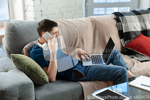 Image of Young focused man studying at home during online courses or free information by hisself