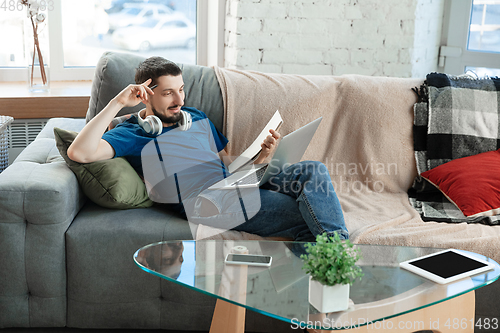 Image of Young focused man studying at home during online courses or free information by hisself