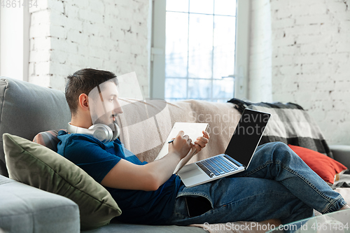 Image of Young focused man studying at home during online courses or free information by hisself