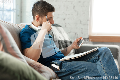 Image of Young focused man studying at home during online courses or free information by hisself