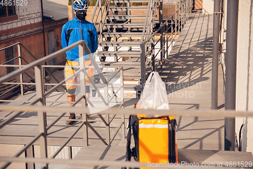 Image of Contacless delivery service during quarantine. Man delivers food and shopping bags during isolation