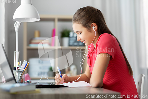 Image of student girl in earphones learning at home