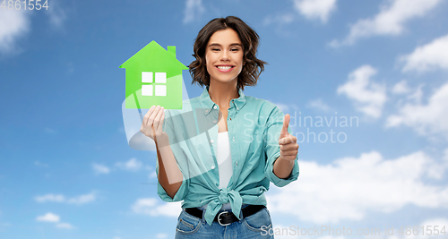 Image of smiling woman with green house showing thumbs up