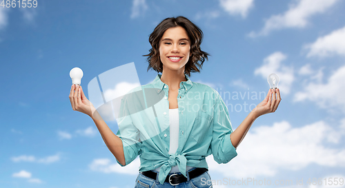 Image of smiling woman comparing different light bulbs