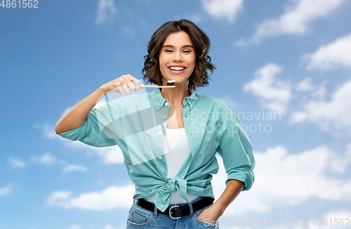 Image of smiling woman with toothpaste on wooden toothbrush