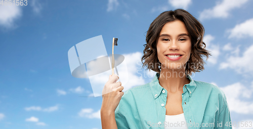 Image of smiling young woman with wooden toothbrush