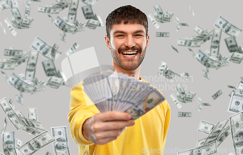 Image of smiling young man in yellow sweatshirt with money