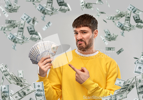 Image of displeased man in sweatshirt with dollar money