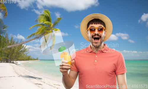 Image of happy man in straw hat with juice on beach