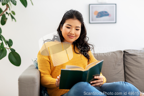 Image of asian young woman reading book at home