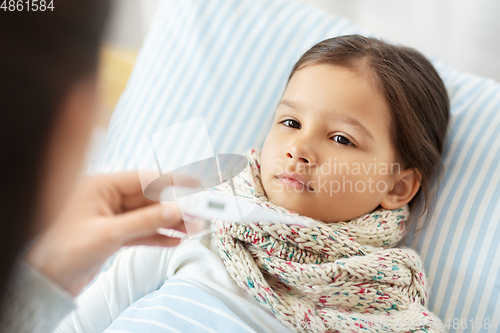 Image of mother measuring temperature of sick daughter