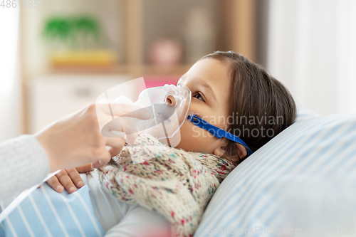 Image of mother and sick daughter with oxygen mask in bed