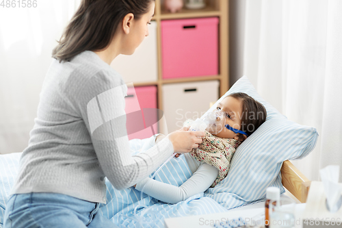 Image of mother and sick daughter with oxygen mask in bed