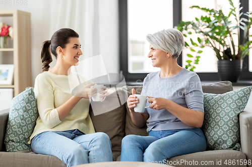 Image of senior mother and adult daughter drinking coffee