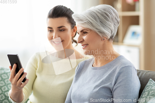 Image of daughter and senior mother with smartphone at home