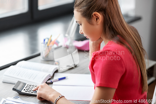 Image of student girl counting on calculator at home