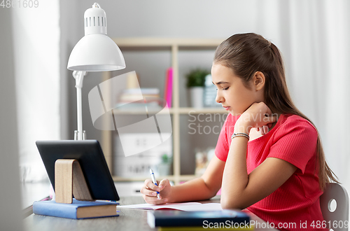 Image of teenage student girl writing to notebook at home