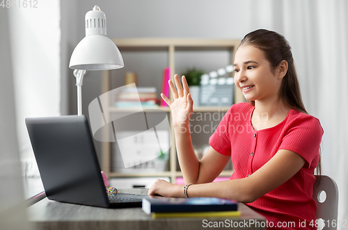 Image of student girl with laptop having video call at home