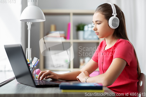 Image of girl in headphones with laptop computer at home