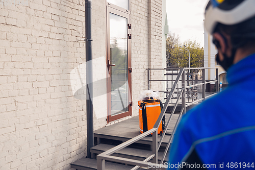 Image of Contacless delivery service during quarantine. Man delivers food and shopping bags during isolation