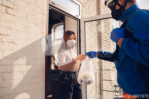 Image of Contacless delivery service during quarantine. Man delivers food and shopping bags during isolation