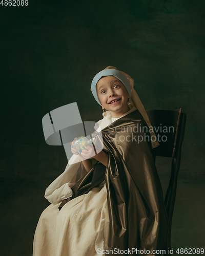 Image of Medieval little girl as a lady with a pearl earring on dark studio background. Concept of comparison of eras, childhood. Stylish creative design, art vision, new look of artwork.