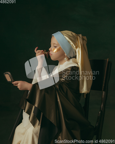 Image of Medieval little girl as a lady with a pearl earring on dark studio background. Concept of comparison of eras, childhood. Stylish creative design, art vision, new look of artwork.