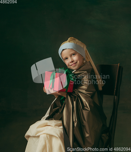 Image of Medieval little girl as a lady with a pearl earring on dark studio background. Concept of comparison of eras, childhood. Stylish creative design, art vision, new look of artwork.