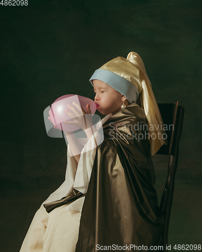 Image of Medieval little girl as a lady with a pearl earring on dark studio background. Concept of comparison of eras, childhood. Stylish creative design, art vision, new look of artwork.