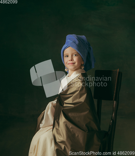 Image of Medieval little girl as a lady with a pearl earring on dark studio background. Concept of comparison of eras, childhood. Stylish creative design, art vision, new look of artwork.