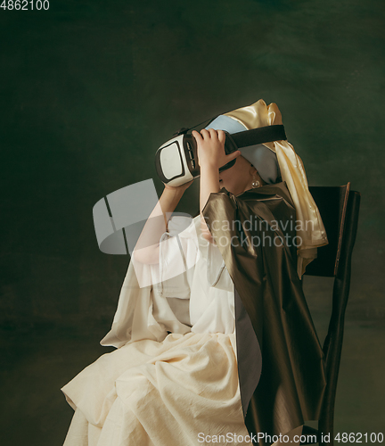 Image of Medieval little girl as a lady with a pearl earring on dark studio background. Concept of comparison of eras, childhood. Stylish creative design, art vision, new look of artwork.