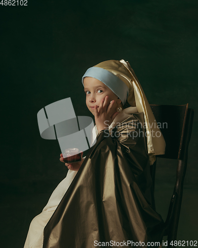 Image of Medieval little girl as a lady with a pearl earring on dark studio background. Concept of comparison of eras, childhood. Stylish creative design, art vision, new look of artwork.