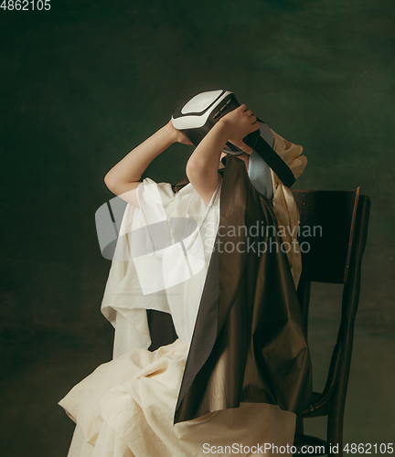 Image of Medieval little girl as a lady with a pearl earring on dark studio background. Concept of comparison of eras, childhood. Stylish creative design, art vision, new look of artwork.