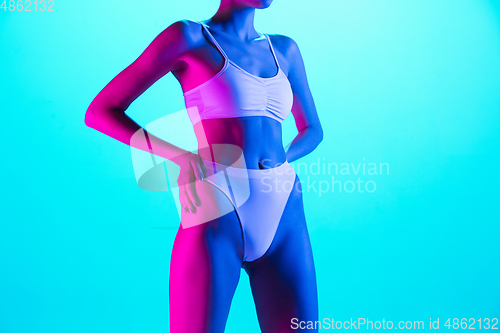 Image of Beautiful female body on blue background in purple neon light. Beauty, cosmetics, spa, depilation, diet and treatment, fitness concept.