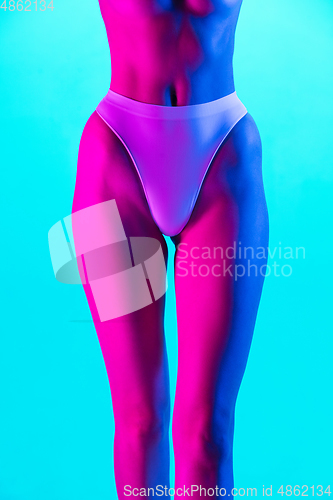 Image of Beautiful female body on blue background in purple neon light. Beauty, cosmetics, spa, depilation, diet and treatment, fitness concept.