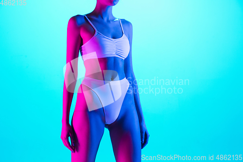 Image of Beautiful female body on blue background in purple neon light. Beauty, cosmetics, spa, depilation, diet and treatment, fitness concept.