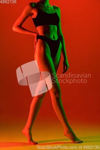 Image of Beautiful female model on orange background in neon light. Beauty, cosmetics, spa, depilation, diet and treatment, fitness concept.