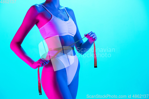 Image of Beautiful female body on blue background in purple neon light. Beauty, cosmetics, spa, depilation, diet and treatment, fitness concept.